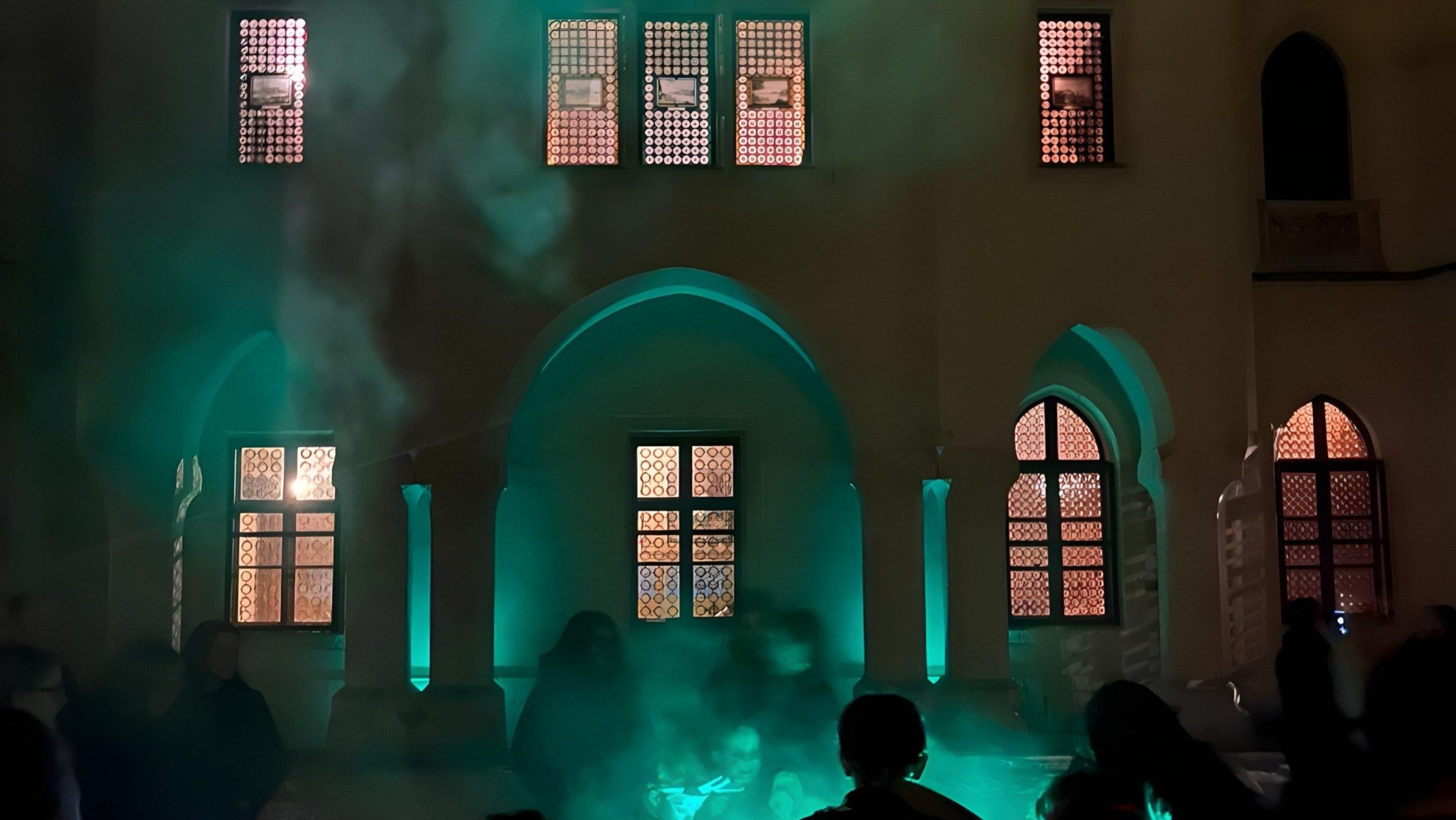 Blick im dunkeln auf eine Seite vom Schloss vor der Menschen stehen und Rauch aufsteigt.