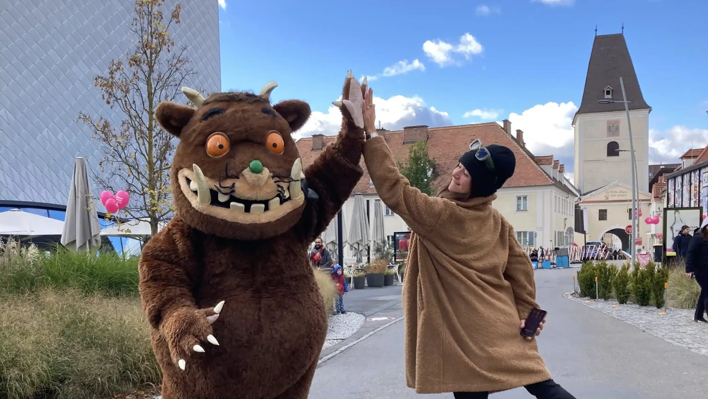 Grüffelo klatscht mit einer Dame ein.